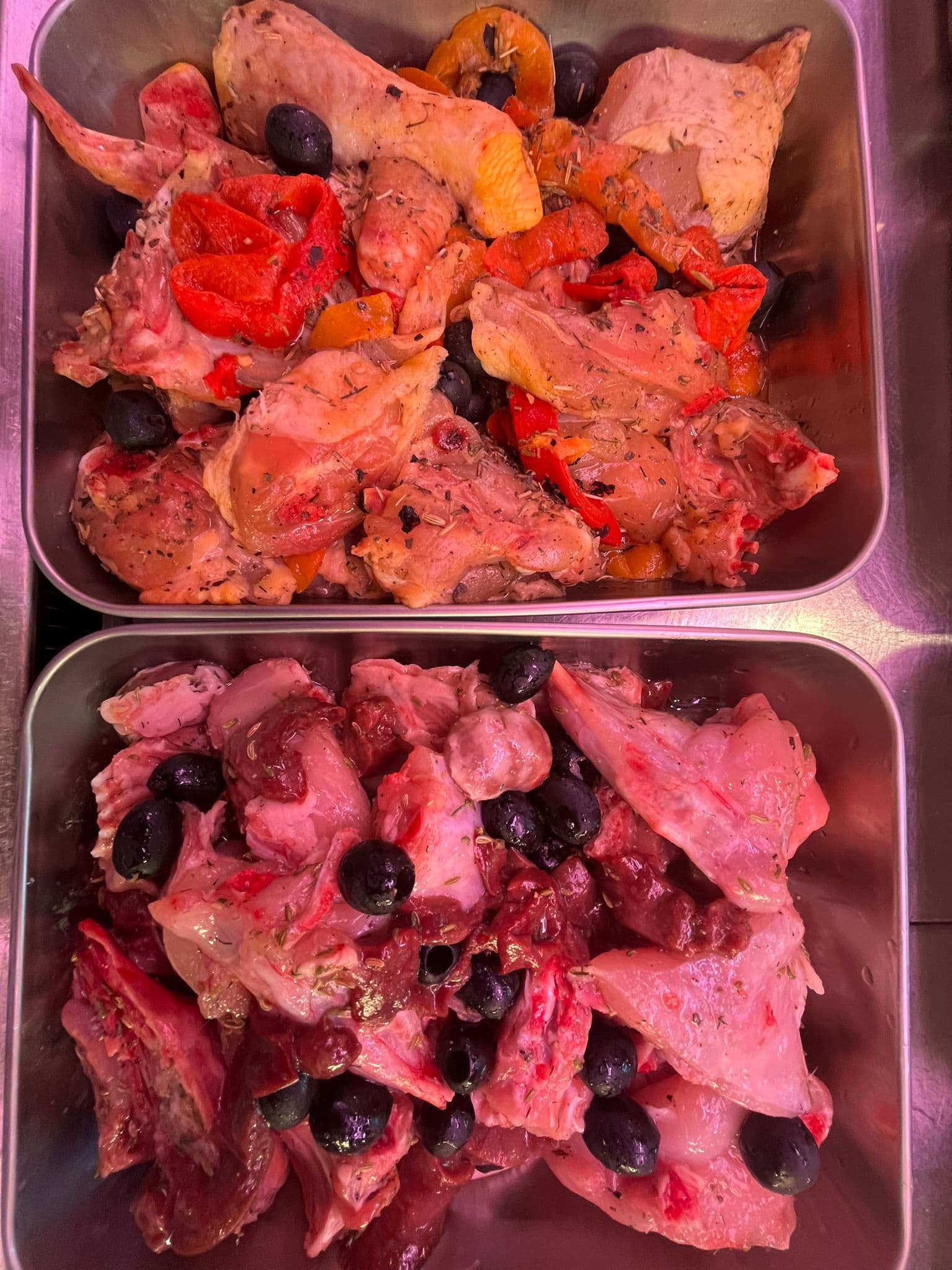 Le teglie della gastronomia: pollo e coniglio conditi con olive, peperoni ed erbe, pronti per il forno
