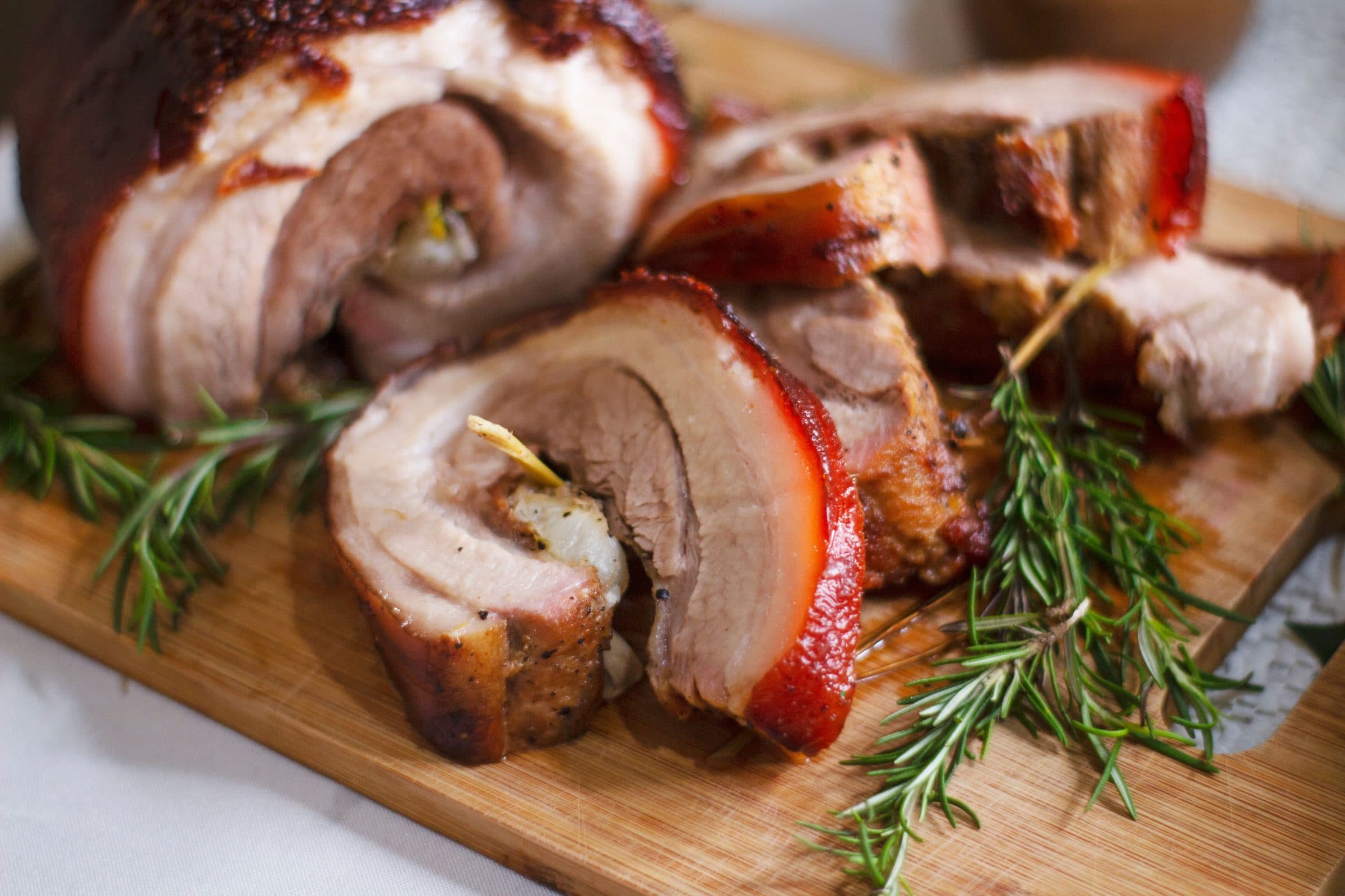 Porchetta affettata sul tagliere, con rametti di rosmarino